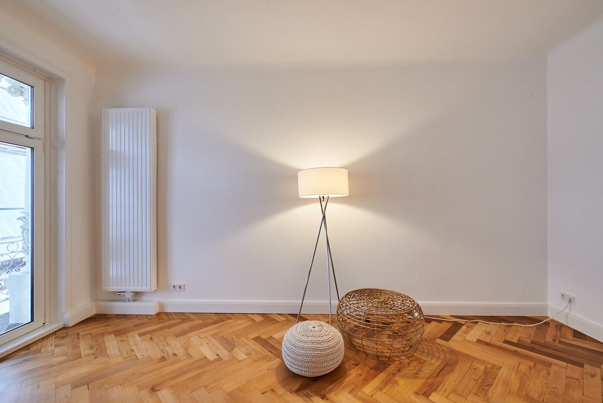 Empty room with parquet flooring and a floor lamp